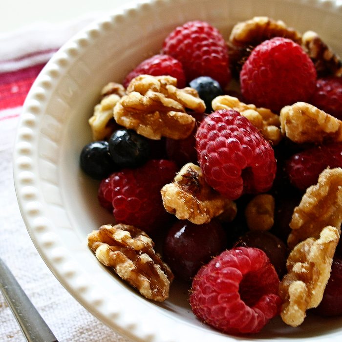 Breakfast of berries and walnuts in a vintage bowl, fork and red striped linen.