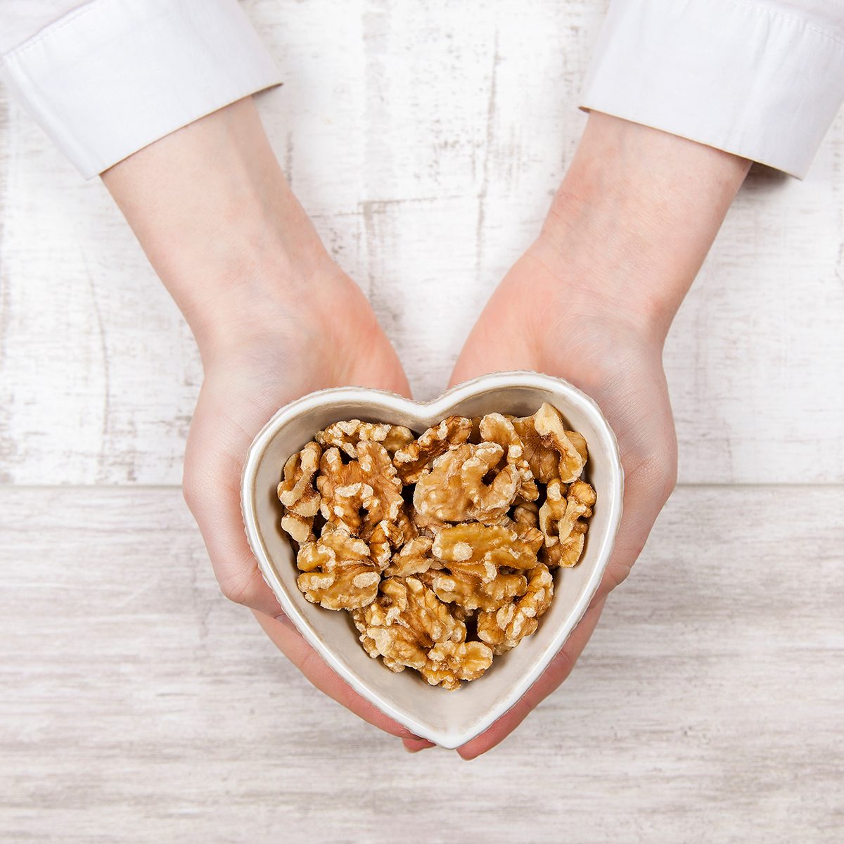 Walnuts in woman hands on white background.