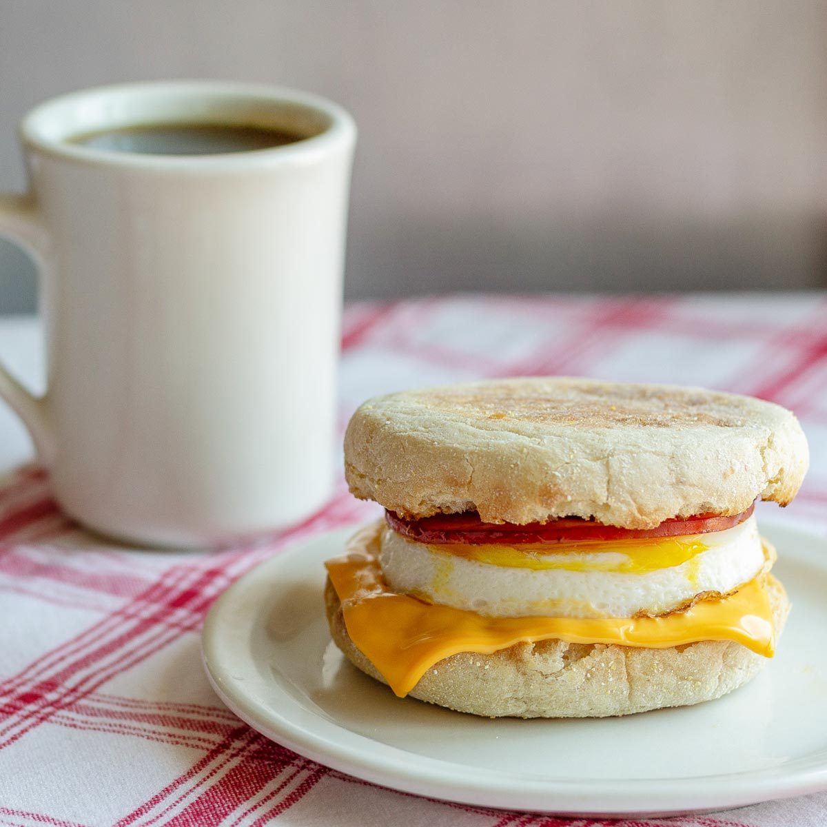 Copycat Mcdonalds Egg Mcmuffin on a plate next to a cup of coffee
