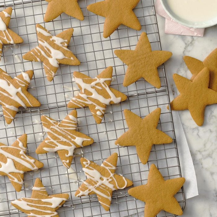 A wire rack with star-shaped cutout cookies cooling before they get drizzled with icing.