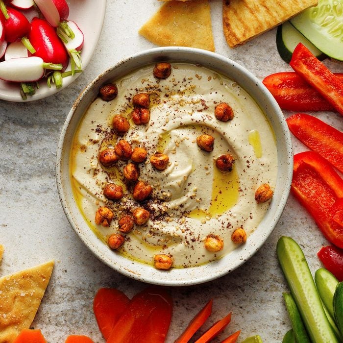 A bowl of homemade hummus topped with olive oil and roasted chickpeas.