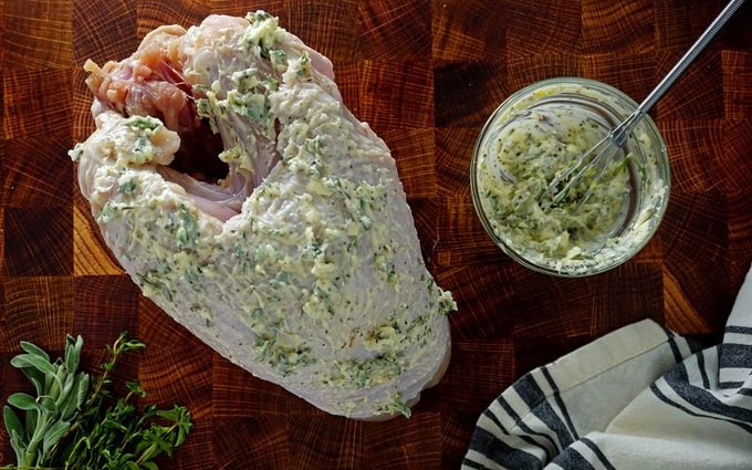 applying the herb butter to the outside of the raw turkey breast before air frying