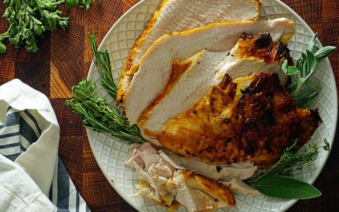 carved air fryer turkey breast on a platter with herbs overhead