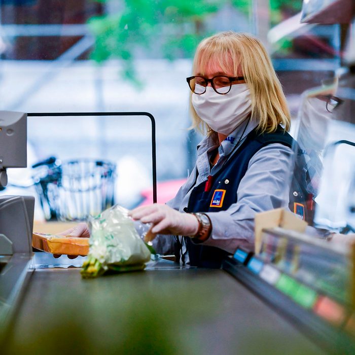 A cashier of food discounter ALDI wears a face mask as she serves a customer in Duesseldorf, western Germany, on April 29, 2020 amid the novel coronavirus COVID-19 pandemic. - From April 29, 2020 in Germany, masks are needed to enter shops, which began to open last week after the government declared its outbreak under control. Nose and mouth coverings are already compulsory on buses, trains and trams. (Photo by Ina FASSBENDER / AFP) (Photo by INA FASSBENDER/AFP via Getty Images)