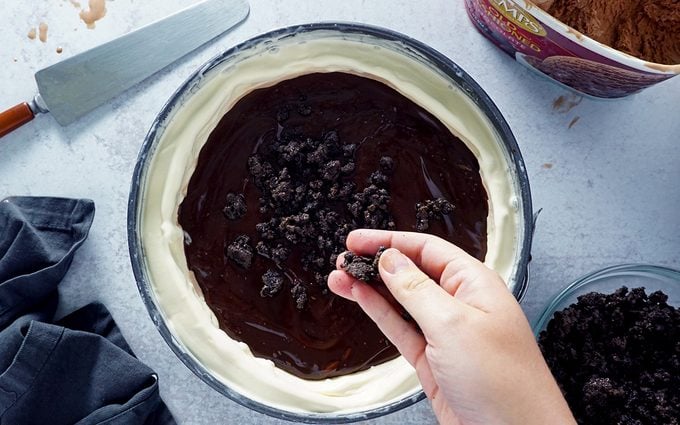 adding chocolate cookie crunch layer to homemade ice cream cake