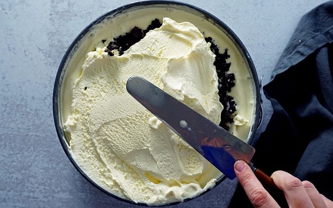 spreading final vanilla ice cream layer on top of ice cream cake
