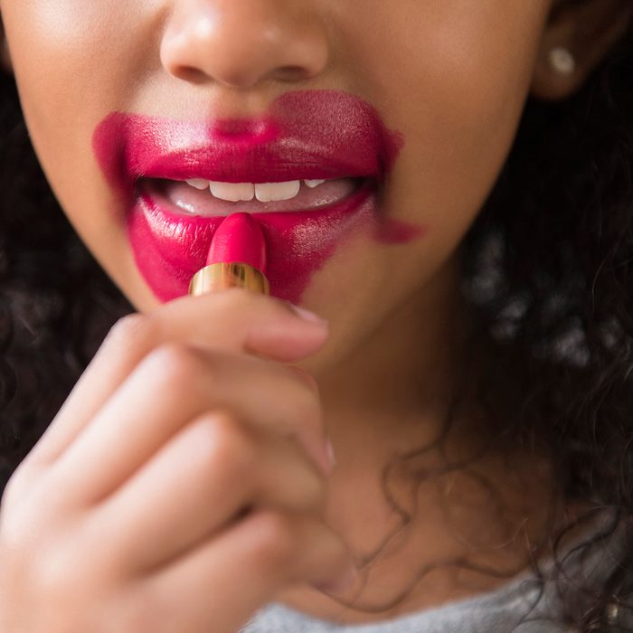 Mixed Race girl applying messy lipstick