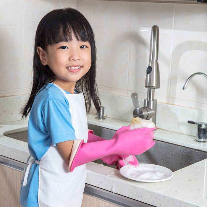 Asian Chinese little girl washing dishes in the kitchen at home