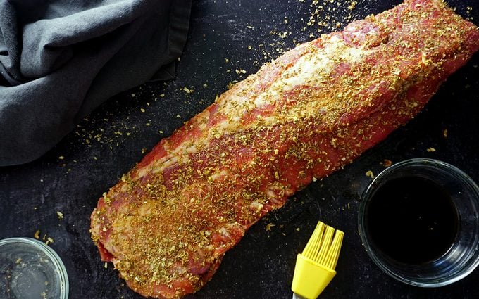 applying a dry rub to baby back ribs before cooking in the oven
