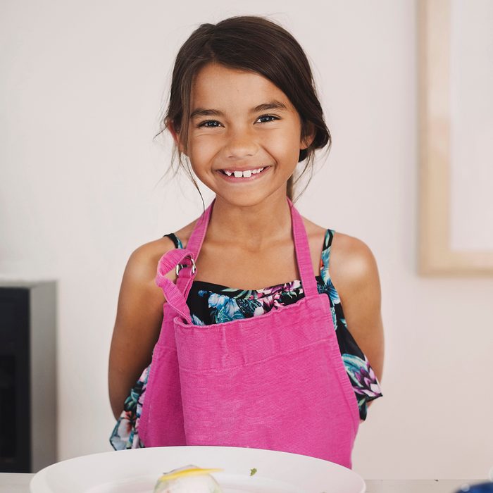 Portrait of happy girl standing at table with Asian food in plate