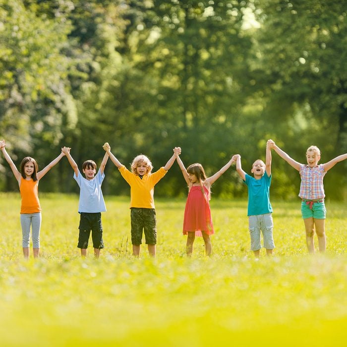 Large group of happy children holding hands in the park and having fun during spring day.