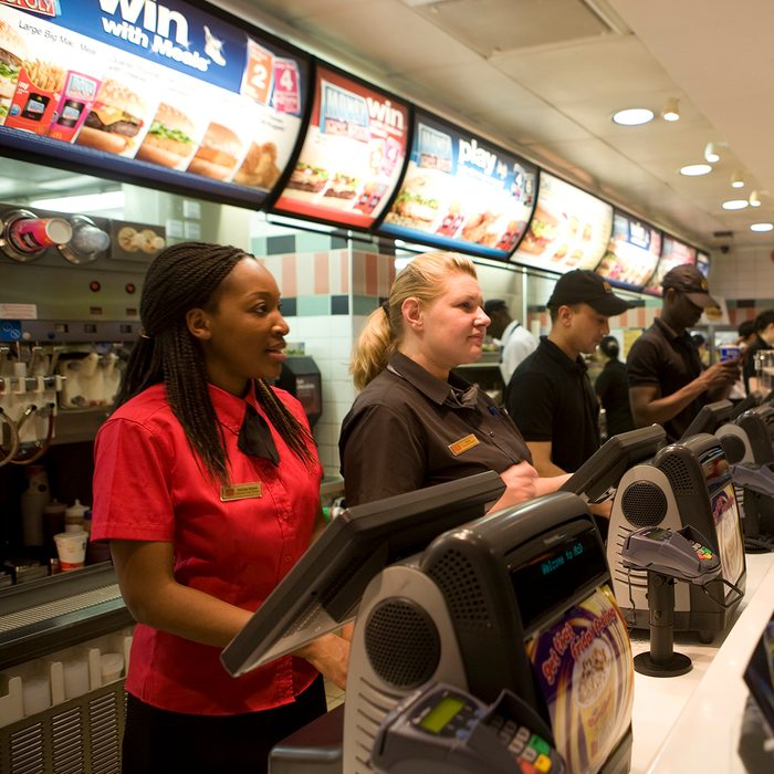 MdDonald's workers, dressed in their new more stylish uniforms take orders from customers at the new trendy coffee bar style ambience and design at the Cannon Street branch of McDonalds in the City of London. This is one of the flagship branches for this new design as the corporation takes on the process of 're-imaging' the fast food chain. This redesign, with new colours: khaki, lime, orange and russet, in a vibrant mixture of geometrics, lines and swooshes has been created for McDonald's by French Designer, Philippe Avanzi. It includes comfortable easy-chairs and stools, drop down lighting and in total, a whole new feel. This is part of a new global strategy to give McDonalds branches in different countries a uniquely local character, both in terms of the decor and some of the food served. (Photo by Gideon Mendel/Corbis via Getty Images)