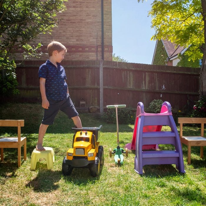 Boy walking on toys arranged in yard