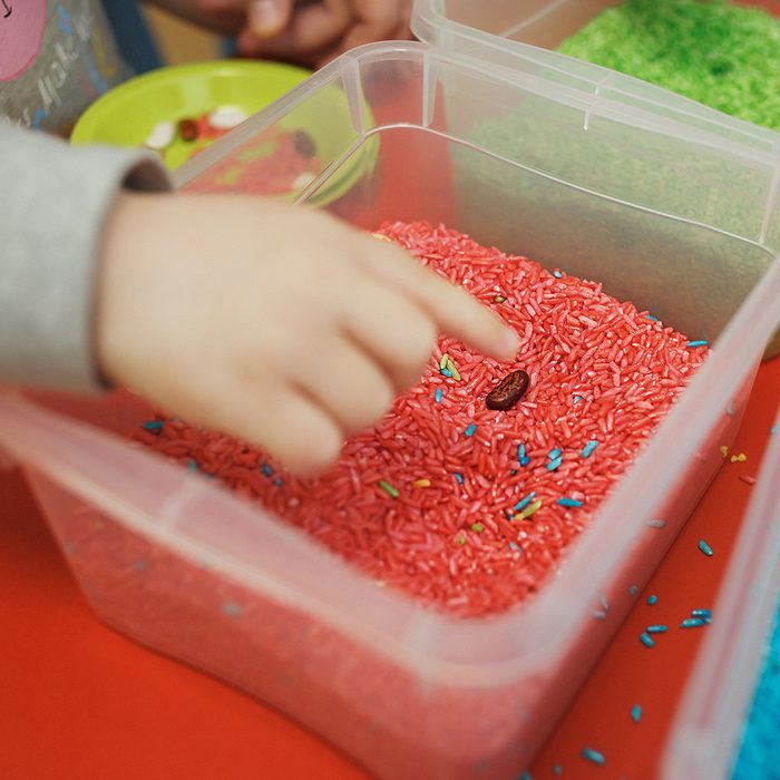 Children play educational games with a sensory bin in kindergarten.
