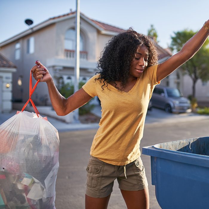 african american woman taking out the trash in las vegas neighborhood during the day