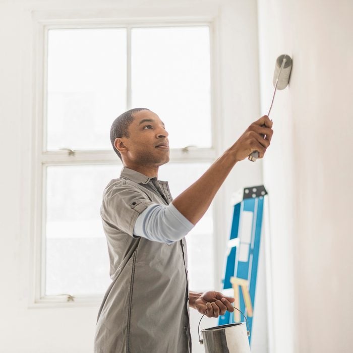 Black man painting wall of home