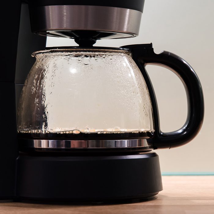 Black coffee machine in modern kitchen from side view. Soft colors, less post-processing. Blue glass plate in the background. Soft grain. Large copy space!