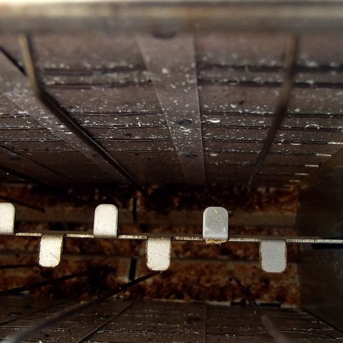 Close up of the inside of a used toaster with grill and crumbs.