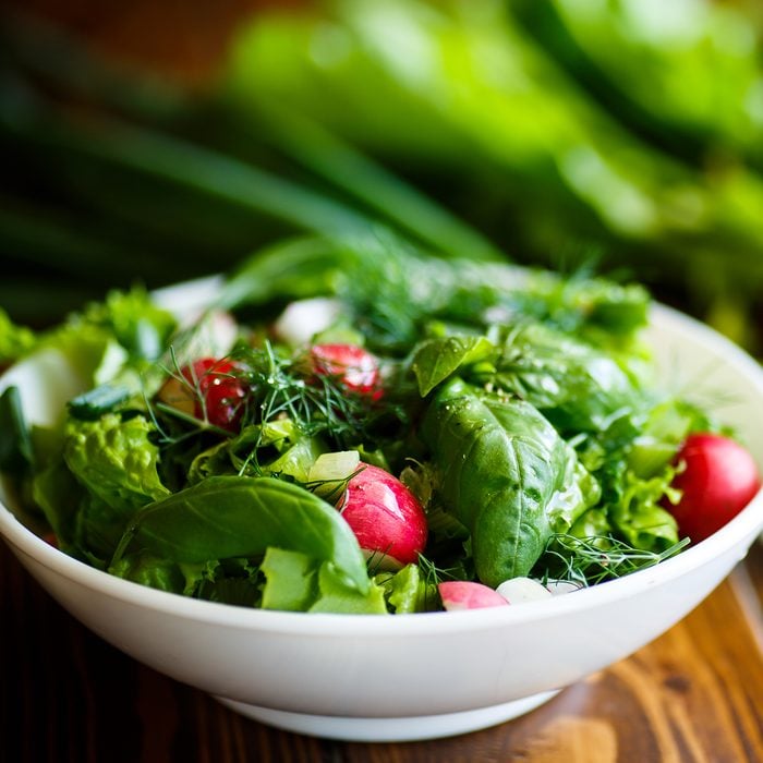 Spring salad from early vegetables, lettuce leaves, radishes and herbs in a white bowl
