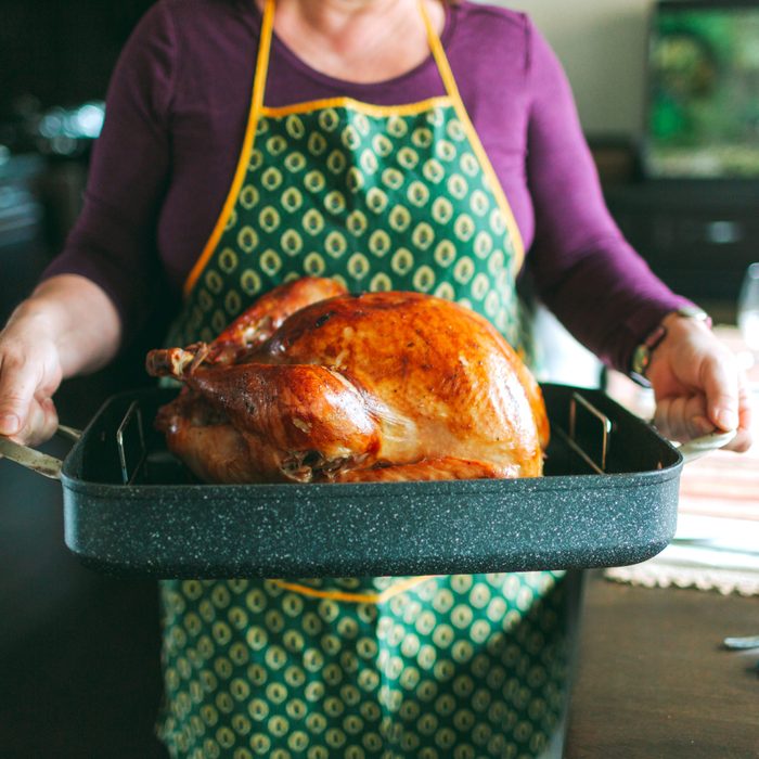 Midsection Of Woman Carrying Tray With Roast Turkey In Kitchen