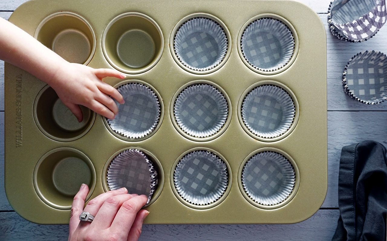 putting liners in a muffin tin with toddler