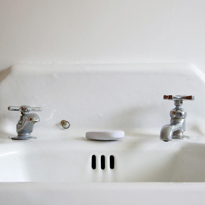 A retro white sink with old fashioned faucets and a bar of soap.