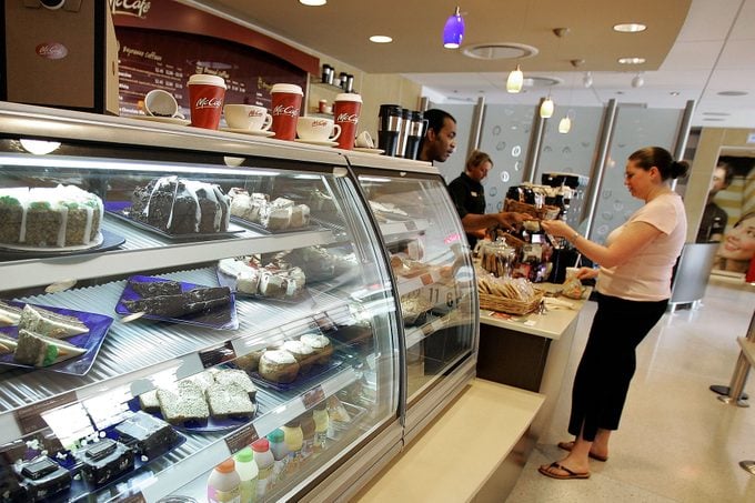 Female pays McCafe employee for her coffee drink beyond a pastry display case at a new McCafe located in a newly constructed McDonald's restaurant 