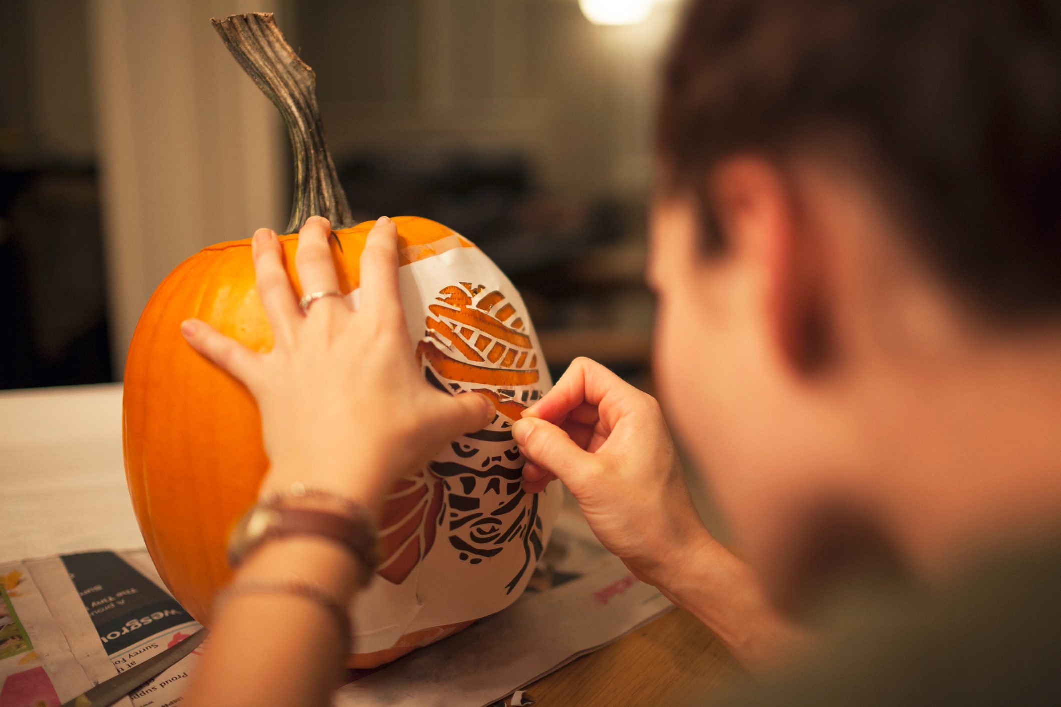 young woman stenciling a pumpkin