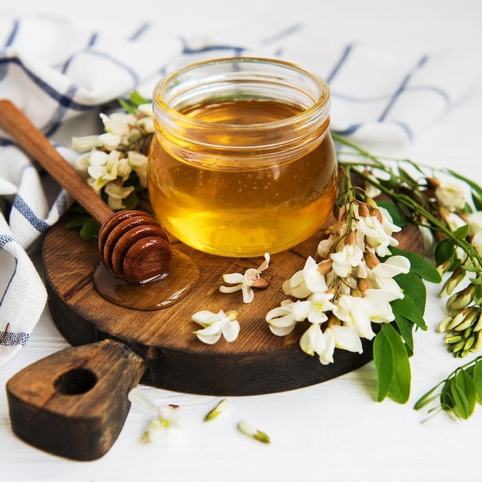 Honey with acacia blossoms on a wooden background