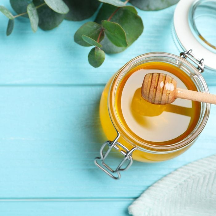 Flat lay composition with fresh honey on light blue wooden table. Space for text