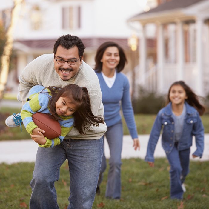 Family playing football in front yard