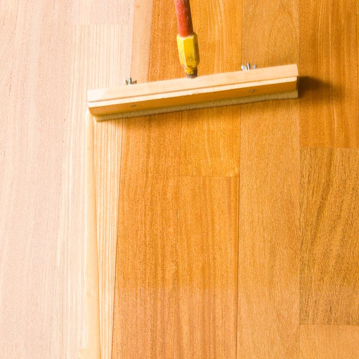 Squeegee Style Brush Applying Clear Polyurethane to Hardwood Floor