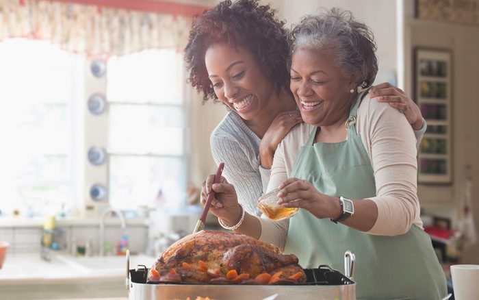 Mother and daughter cooking family thanksgiving dinner together in kitchen