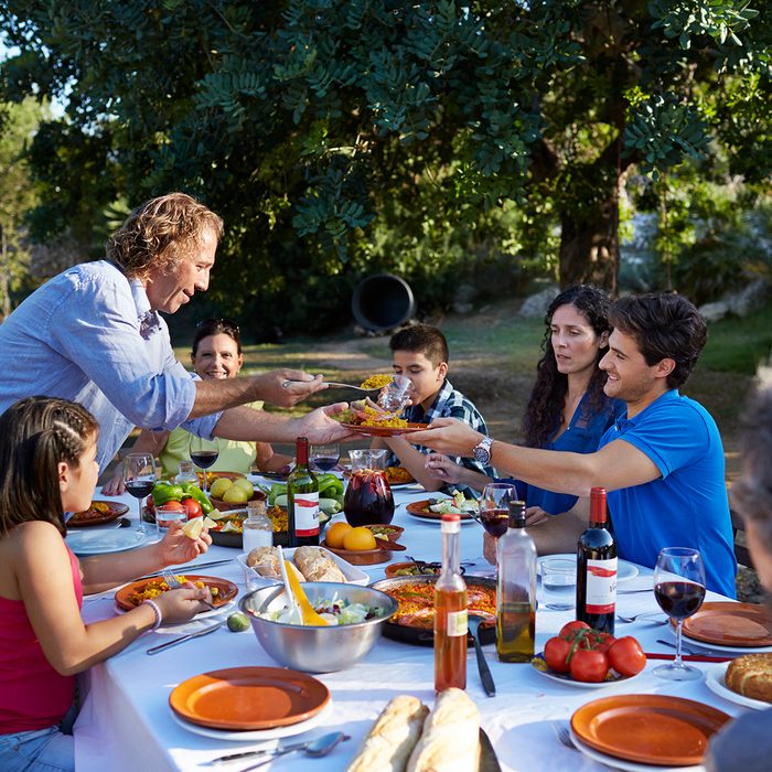 Multigenerational family together at dinner table at garden party in the sunset