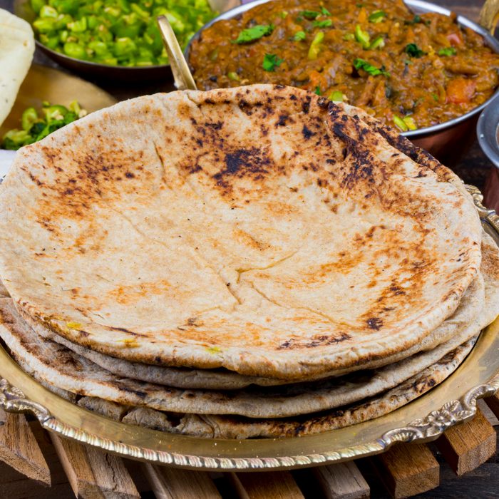 Indian Cuisine Chapati Also Called Roti, Flatbread, Chapathi or Chapatti Served With Sev Tamatar, Gatta Curry, Raita, Papad or Onion on Wooden Background