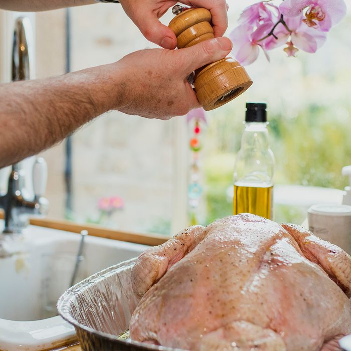 Close up shot of a man's hands as he seasons a turkey ready for thanksgiving dinner.