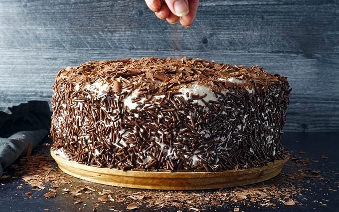 covering Swiss Pastry Shop Black Forest Cake generously with chocolate sprinkles and shavings