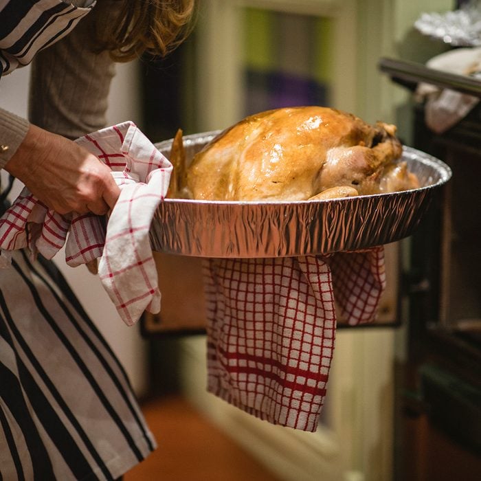 A close-up shot of an unrecognisable woman taking a turkey out of the oven at Christmas.