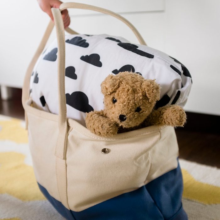 Girl's hand holding bag with blanket and teddy bear uses for reusable bags