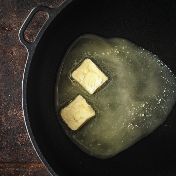 Pieces of butter in the hot pan on the metal background top view