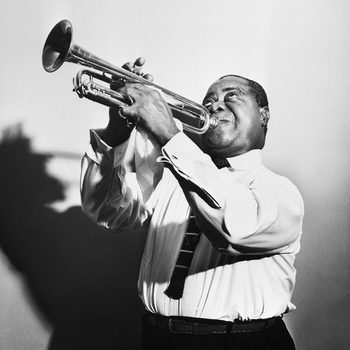 Louis Armstrong blows a horn in a publicity picture.