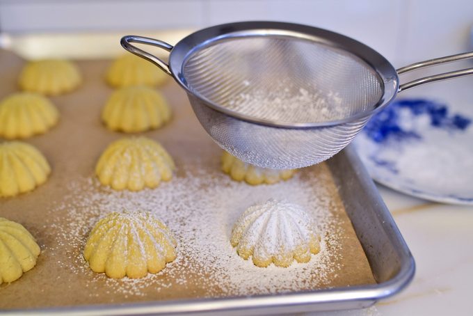 Confectioners' sugar in a fine mesh sieve sifted over baked ma'amoul cookies