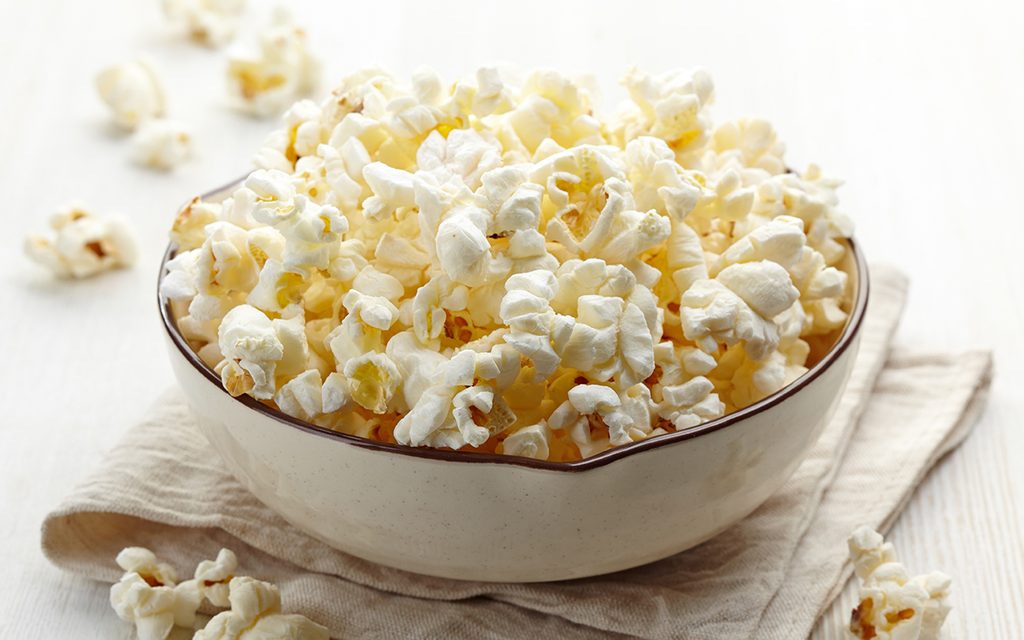 Bowl of fresh popcorn on white wooden background - how to make air popped popcorn
