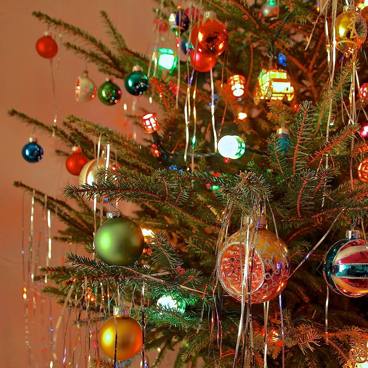 Close up of Christmas Tree decorated with antique glass baubles and coloured lights in kitsch retro 70s style