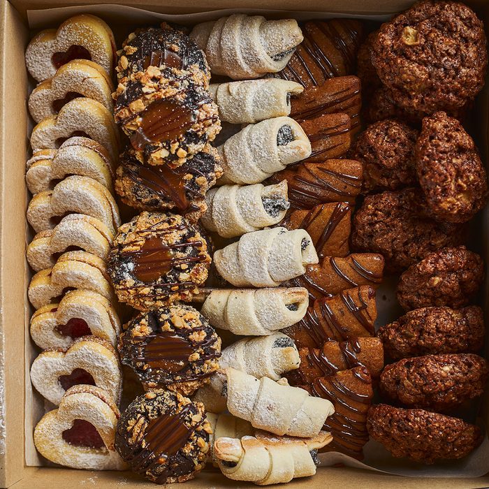 Top view of various mini Christmas pastry in the cardboard box on wooden table
