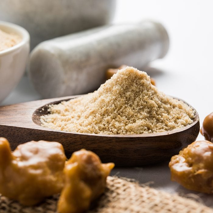 indian spices Asafoetida cake and powder or Hing or Heeng which is an important ingredient in Indian food recipes with big wooden spoon and mortar, selective focus