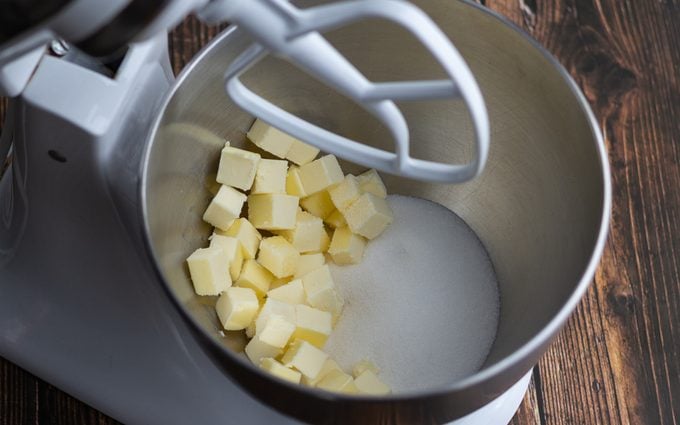 how to cream butter and sugar Stand mixer bowl with sugar and cubes of butter.