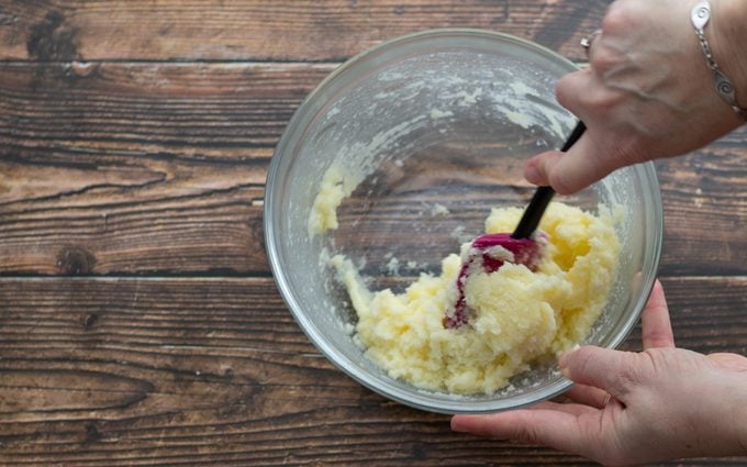 Hands holding bowl and spatula to stir ingredients in bowl. how to cream butter and sugar