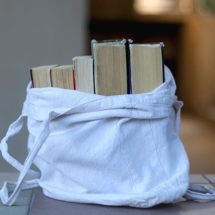 Canvas tote bag filled with old books. Selective focus.