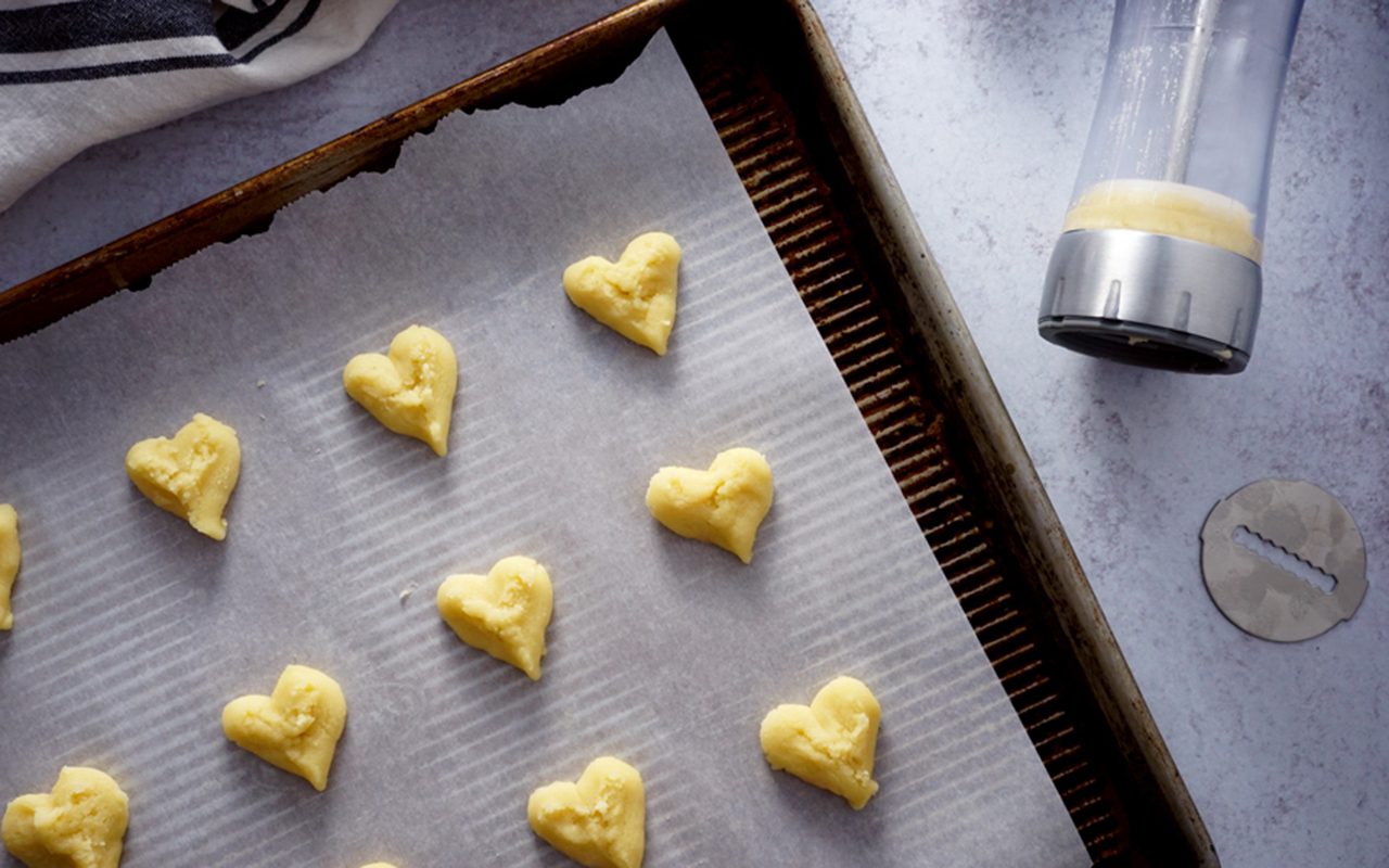 heart-pressed cookies on baking sheet how to make butter cookies